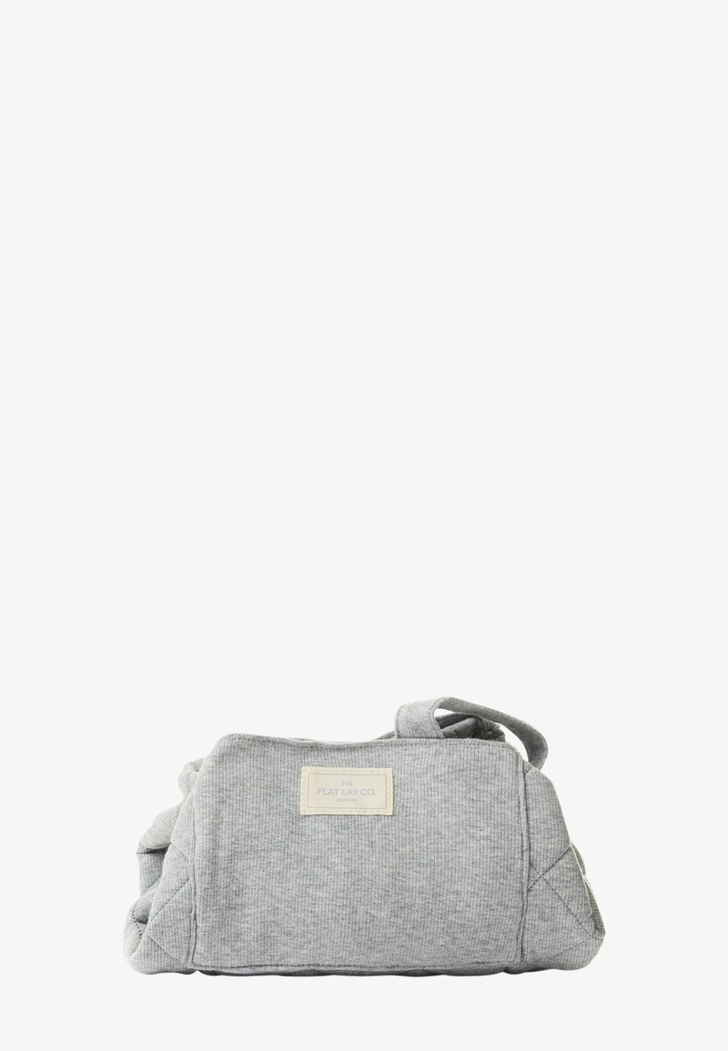 Grå stoffveske med en teksturert overflate, firkantet form og korte håndtak. Har en etikett med "THE FLAT LAY CO." på fronten.
