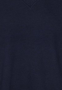 Granatowy sweter w serek wykonany z miękkiej dzianiny, charakteryzujący się gładką fakturą i brakiem widocznych wzorów czy akcentów.