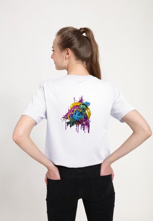 Bílý bavlněný tričko s barevným grafickým designem na zadní straně, s fialovými skvrnami a postavou v modrých a zelených tónech.