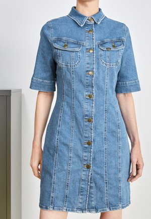 Sukienka dżinsowa z kołnierzykiem, krótkimi rękawami, przednimi kieszeniami oraz zapięciem na guziki wzdłuż środka. Jasnoniebieski kolor i pionowe szwy.