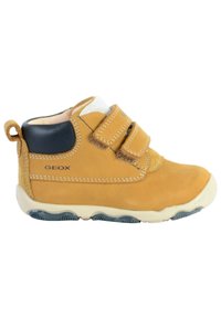 Botines de cuero marrón claro con acentos azules, dos tiras de velcro y suela texturizada para agarre; forro suave visible en la parte superior. Presencia de la marca GeoX.