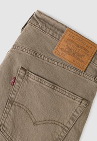 Καφέ τζιν παντελόνι Levi’s από DENIM με πίσω τσέπη που έχει δερμάτινη ετικέτα μάρκας με μέγεθος W32 L32 και κόκκινη ετικέτα Levi’s.