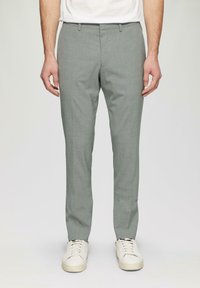 Helles graue, maßgeschneiderte Hose, schlanke Passform, strukturierter Stoff, flacher Vorderteil, Gürtelschlaufen, getragen mit weißen Sneakers.