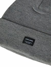 Gray knitted beanie hat featuring a fold-over cuff and a black label with white text. The texture is smooth with a ribbed pattern.