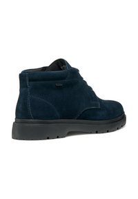Bottes de cheville en daim bleu marine avec une semelle en caoutchouc noir basse, un col rembourré et des détails de couture minimaux sur les côtés. Design à lacets.