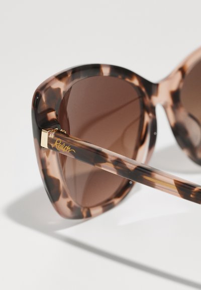 Ochelari de soare în stil cat-eye cu un model țestoasă, lentile de culoare maro și o ramă transparentă. Detaliile aurii includ numele brandului "Ralph."