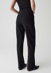 Pantaloni neri elasticizzati con una vestibilità ampia, dotati di una vita elastica e due tasche posteriori, realizzati in un tessuto morbido e confortevole.