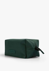 Bolsa de cosméticos rectangular verde, hecha de tejido suave, con un zipper negro y una pequeña etiqueta de la marca en la parte frontal. Diseño compacto.