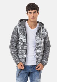 Grauer Reißverschluss-Hoodie mit gemustertem Vorderseite, die weißen grafischen Text zeigt, gerippte Bündchen, eine Kordelzugkapuze und eine weiche Textur.