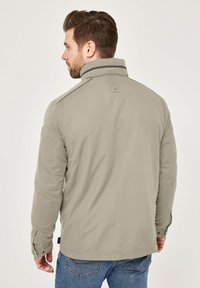 Light gray jacket with a stand collar, buttoned cuffs, and subtle black accents. Smooth texture, tailored fit, and back design detail.