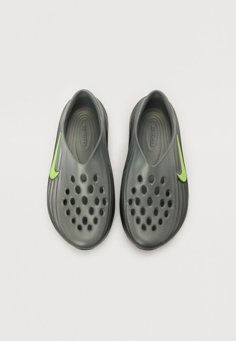 Baskets grises à enfiler avec de grandes aérations, design texturé et un accent de logo Nike vert vif. Matériau en caoutchouc moulé.