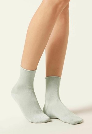 Calcetines de tobillo verde claro, hechos de un material suave y brillante con un diseño acanalado, que presentan un puño clásico para un ajuste seguro.