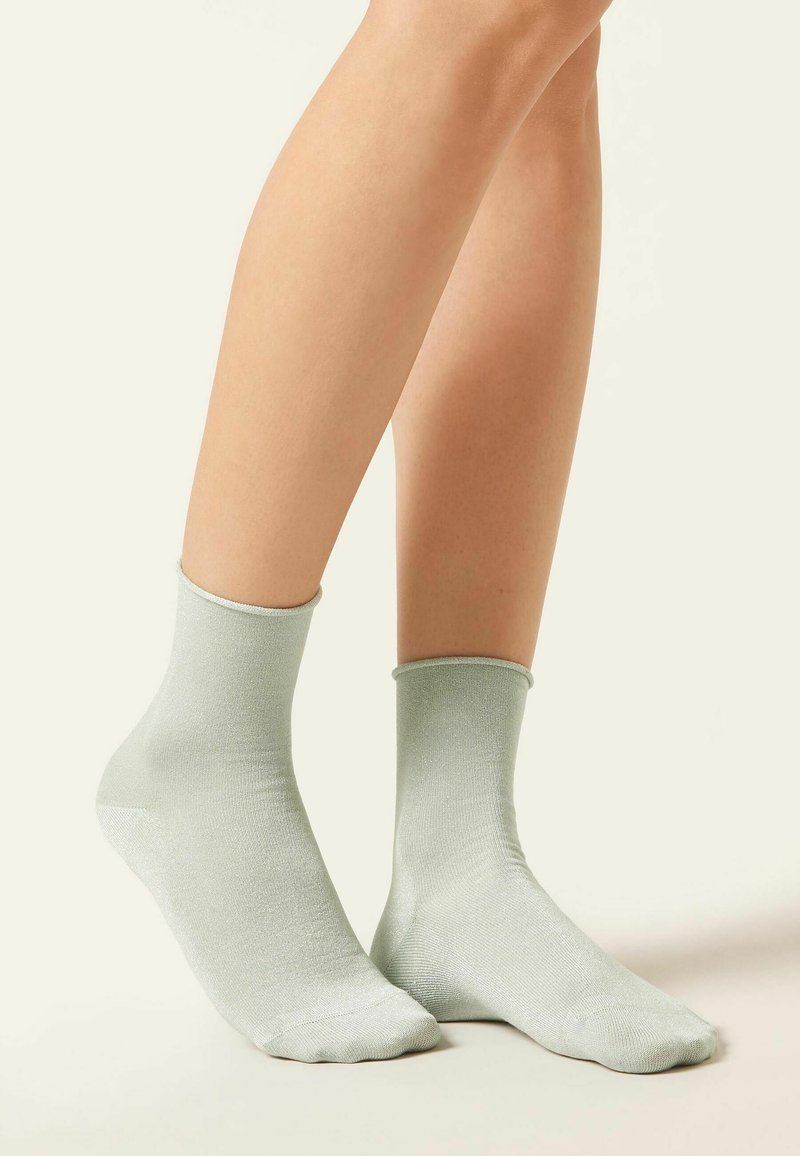 Ljusgröna ankelsockor gjorda av ett slätt, glänsande material med ett ribbat mönster, med en klassisk resårkant för en säker passform.