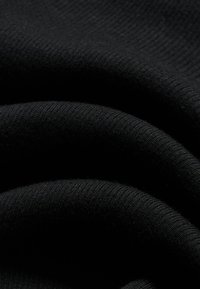 Κοντινό πλάνο μαύρου ριμπ ύφανσης με απαλές πτυχές που αναδεικνύουν την υφή και το σχέδιο πλεξίματος.