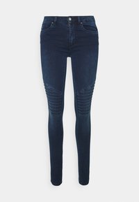 Vaqueros skinny de color azul oscuro hechos de denim, con acentos acanalados en los muslos, diseño clásico de cinco bolsillos y cierre frontal de botón.