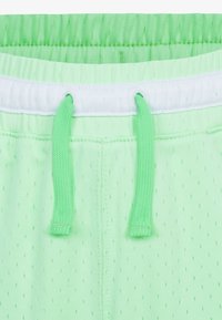 Světle zelené šortky s mřížkovou texturou, vybavené elastickým pasem a bílou šňůrkou. Malé perforace zlepšují prodyšnost.