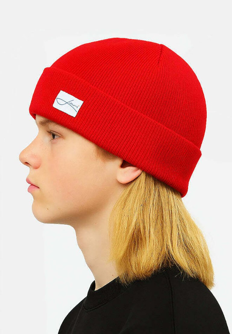 Red knitted beanie with a folded cuff, featuring a white logo patch. Soft texture and close-fitting design. No additional embellishments.