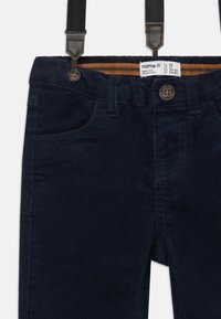 Navy blue corduroy pants with adjustable dark straps; features front pockets, button closure, and textured ribbed fabric detailing.