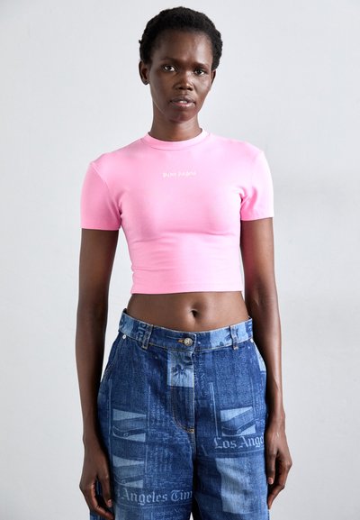 Korte mouwen, aansluitend roze crop top met een ronde halslijn en het "Palm Angels" logo in het wit, gecombineerd met distressed blauwe denim high-waisted broek.