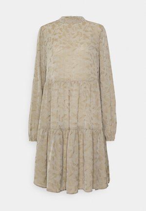 Robe beige à manches longues en tissu texturé, avec un col montant, une jupe en couches et un motif abstrait subtil sur l'ensemble.