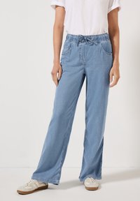 Jasnoniebieskie dżinsowe spodnie o szerokich nogawkach, z elastycznym pasem i sznurkiem. Posiadają dwie boczne kieszenie i luźny krój.