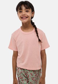 T-shirt rose à manches courtes en tissu doux, avec un col rond et une coupe décontractée, associé à un pantalon vert à imprimé floral.