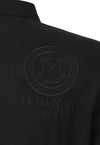 Svart broderad pikétröja med en texturerad logotyp och detaljerna "LA MARTINA SINCE 1987". Mjuk tygkvalitet med en standardkrage.