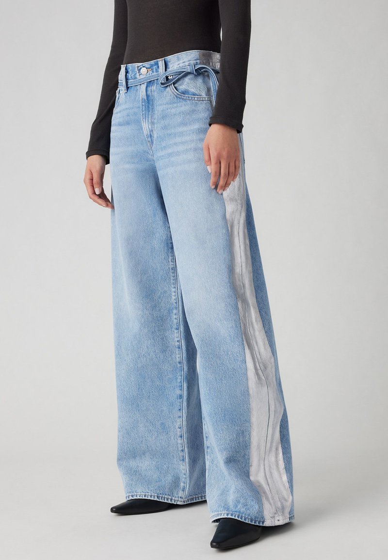 Jeans a gamba larga blu chiaro con una striscia laterale bianca a contrasto, dotati di vita alta e chiusura con bottone, realizzati in tessuto denim.