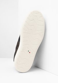 Sneaker nera con superficie superiore in stampa animale testurizzata, suola in gomma bianca con un motivo di battistrada. Logo e dettagli della taglia visibili sulla suola.