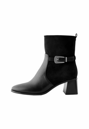 Bottine noire avec une combinaison de cuir lisse et de suède texturé. Bout carré, talon block, et accent en boucle en métal.