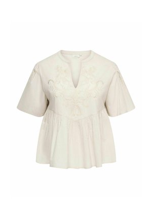 Blouse blanche à manches courtes avec col en V, broderie florale sur la poitrine, coupe ample et tissu froncé sous la poitrine.