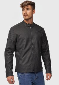 Schwarze Leder-Motorradjacke mit steigendem Kragen, gesteppten Schulterakzenten und Reißverschlusstaschen. Glatte Textur und taillierte Passform.