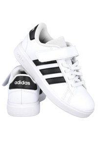 Zapatillas deportivas blancas con detalles en negro. Presentan tres franjas negras, una correa de Velcro y tela texturizada en la lengüeta y el interior.