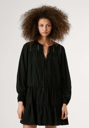 Schwarzes, gestuftes Kleid aus leichtem Stoff, mit einem V-Ausschnitt mit Bindebändern, langen Ärmeln und dezenten dekorativen Nähten am Kragen.