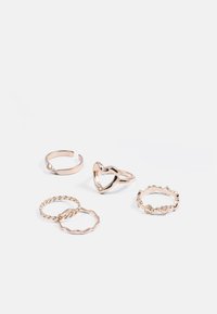 Conjunto de cinco anéis delicados em ouro, incluindo bandas torcidas, um anel com contorno em forma de coração e um anel com pequenas decorações de coração.
