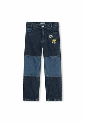 Jean en denim avec un design en patchwork dans des nuances de bleu foncé et clair, avec un tigre brodé et des accents dans un style bande dessinée sur le devant.