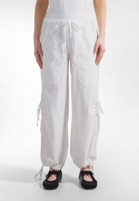 Hvide bomuldsjoggerbukser med elastik i taljen, snøre og sidelommer; med snøre detaljer ved kanten for justerbar pasform.