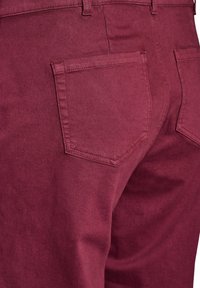 Burgundy rifle so skvelou textúrou, s zadným vreckom s uhlovým okrajom a detailným švom, navrhnuté pre priliehavý vzhľad.
