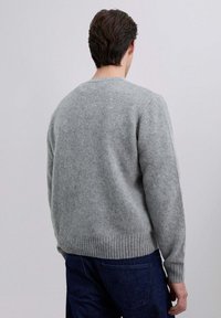 Suéter de lana gris con un acabado texturizado, puños y dobladillo acanalados, y un clásico cuello redondo. Presentado desde la parte posterior.