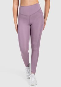 Paarse high-waisted leggings gemaakt van rekbaar materiaal, met platte naden en een soepele textuur, gecombineerd met witte sportieve schoenen.