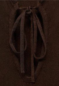 Hnědý pletený top s texturovaným, otevřeným výstřihem a zavazováním. Látka je hladká, s jemným žebrovaným vzorem kolem okrajů.