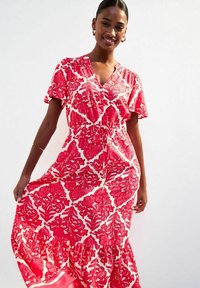 Maxikleid aus leichtem Stoff, mit einem roten Blumenmuster auf weißem Hintergrund. Kurze Ärmel, V-Ausschnitt und geraffte Taillendetails.