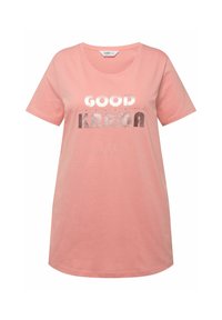 Camiseta de algodón rosa claro con escote redondeado y mangas cortas, que presenta un texto en plateado metálico que dice "BUENA KARMA" en diferentes tipografías.