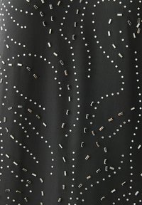 Tissu noir orné de sequins métalliques rectangulaires et circulaires dispersés, créant un motif en ondulation sur la surface.