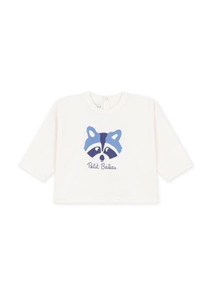 T-shirt bébé blanc à manches longues avec un motif de visage de raton laveur bleu et le texte "Petit Bateau" imprimé sous l’image.