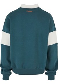 Hanorac oversized teal cu o dunga albă, manșete și tiv cu textura în relief, și cu "Interzis" brodat în portocaliu la gâtul din spate.
