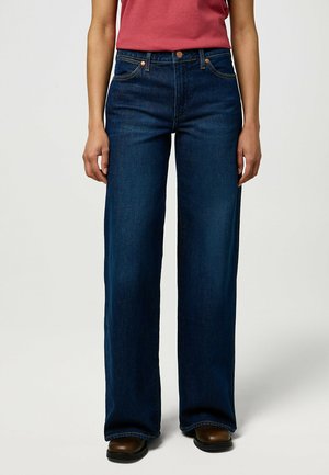 Jean large en denim de couleur bleu foncé. Les caractéristiques incluent une taille mi-haute, des accents de couture clairs et un design classique à cinq poches.