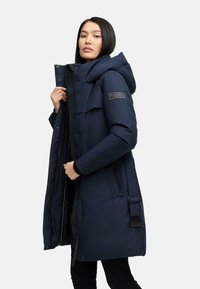 Navy blue parka coat with a large hood, zippered front, and side pockets. Features a patch logo and adjustable waist strap. Smooth fabric.