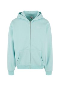 Lyseblå zip-up hoodie lavet af blødt stof, med en frontlomme, ribbede manchetter og et lille broderet logo på brystet.