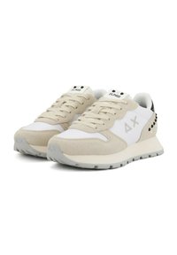 Sneakers beige chiaro e bianchi in materiali scamosciati e a rete. Presentano un design con lacci, un logo sulla linguetta e dettagli con borchie nere sul tallone.